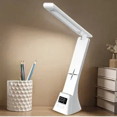 One white desk light, on a shelf with books and a cup.