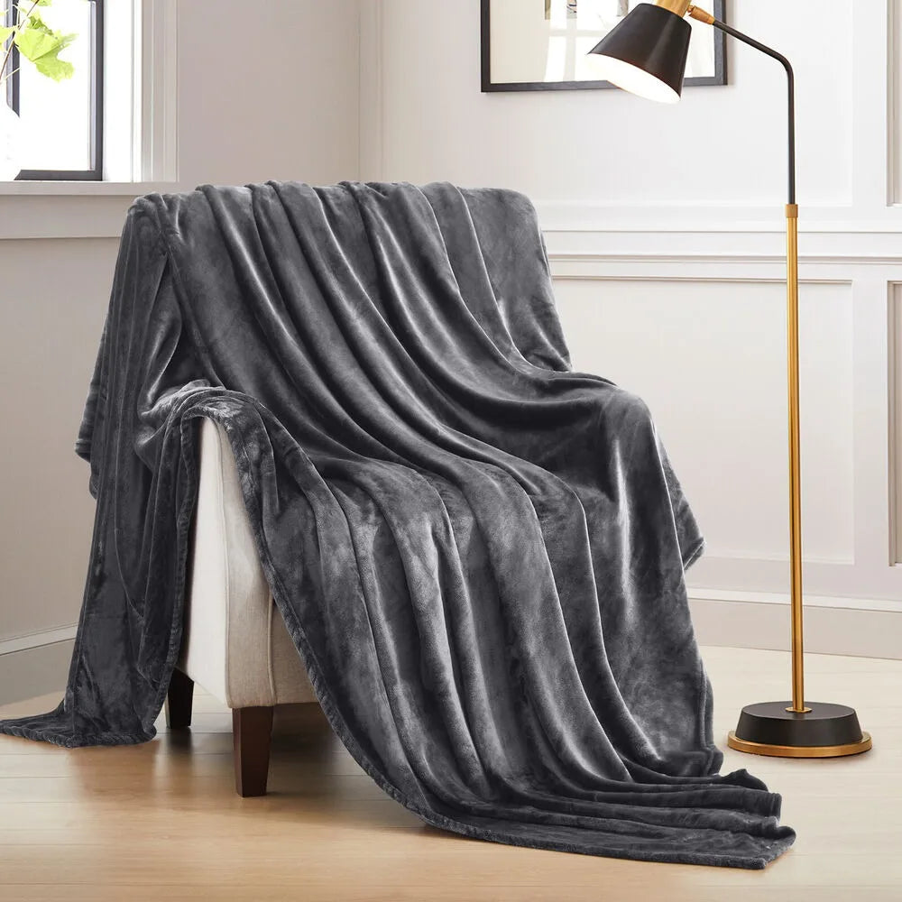 A stone grey blanket draped over a chair in a room with a lamp and window.