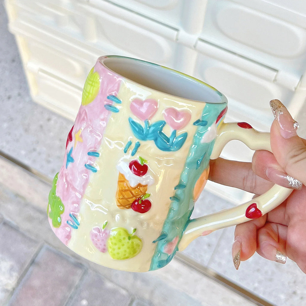 Colorful mug with floral designs held by a hand on a light background