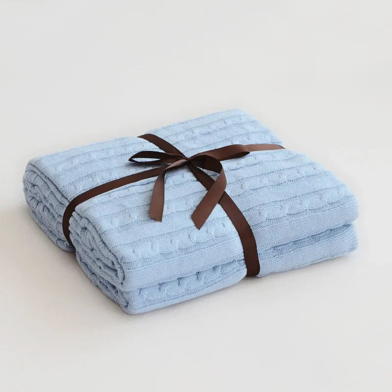 Folded blue blanket with a brown ribbon on a light gray background