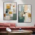 Two abstract paintings on a wall above a pink sofa in a living room setting.