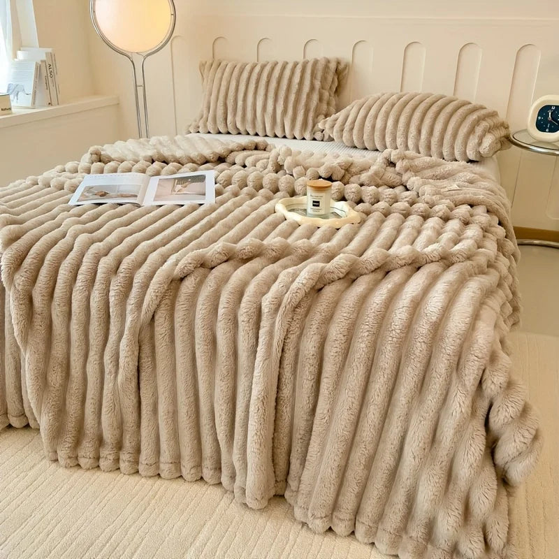 Beige fluffy blanket draped over a bed in a cozy bedroom setting.