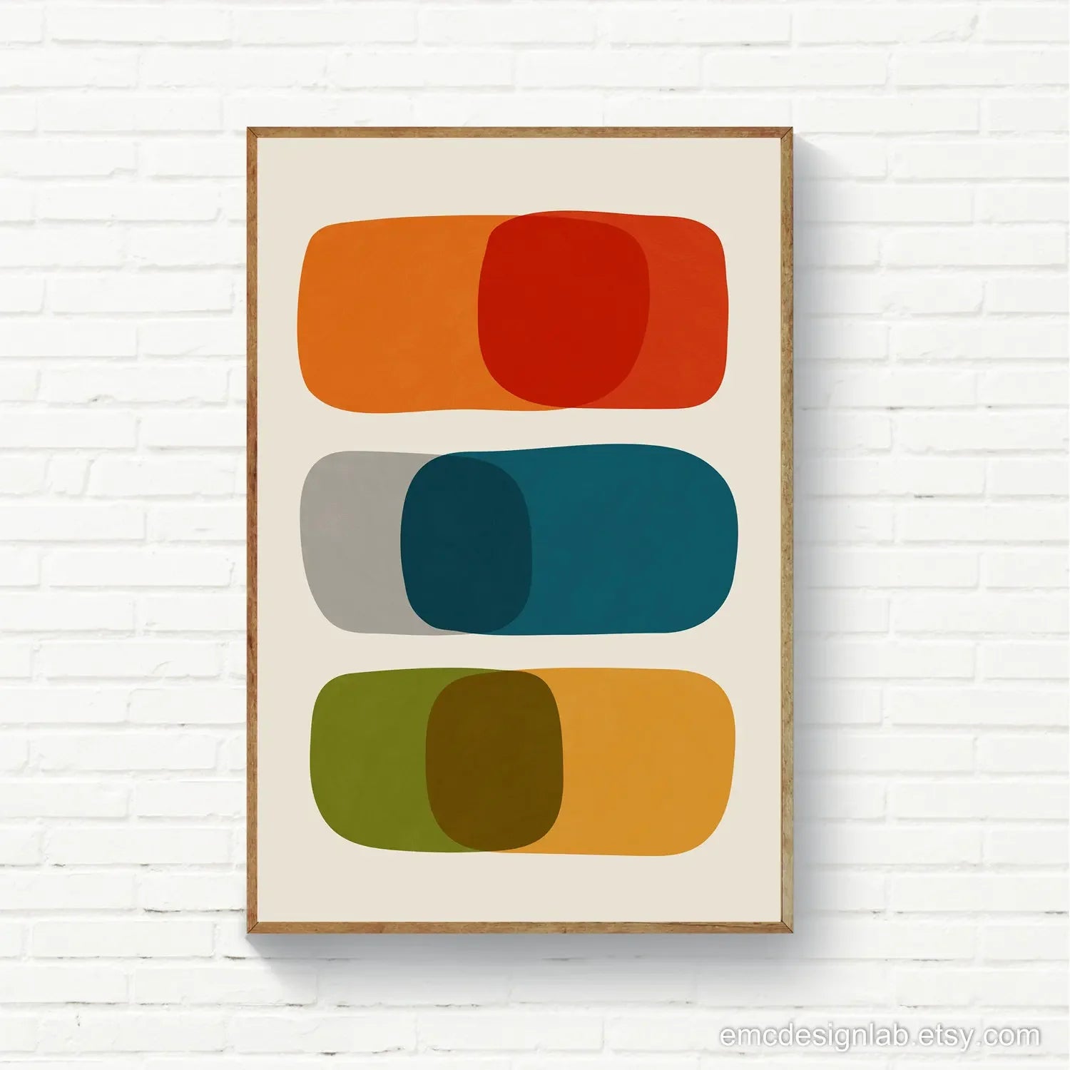 Framed abstract art print with colorful geometric shapes on a white brick wall.