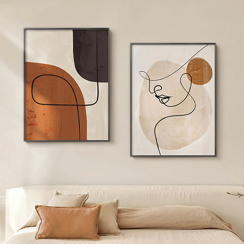 Two abstract art pieces on a wall above a sofa with pillows.