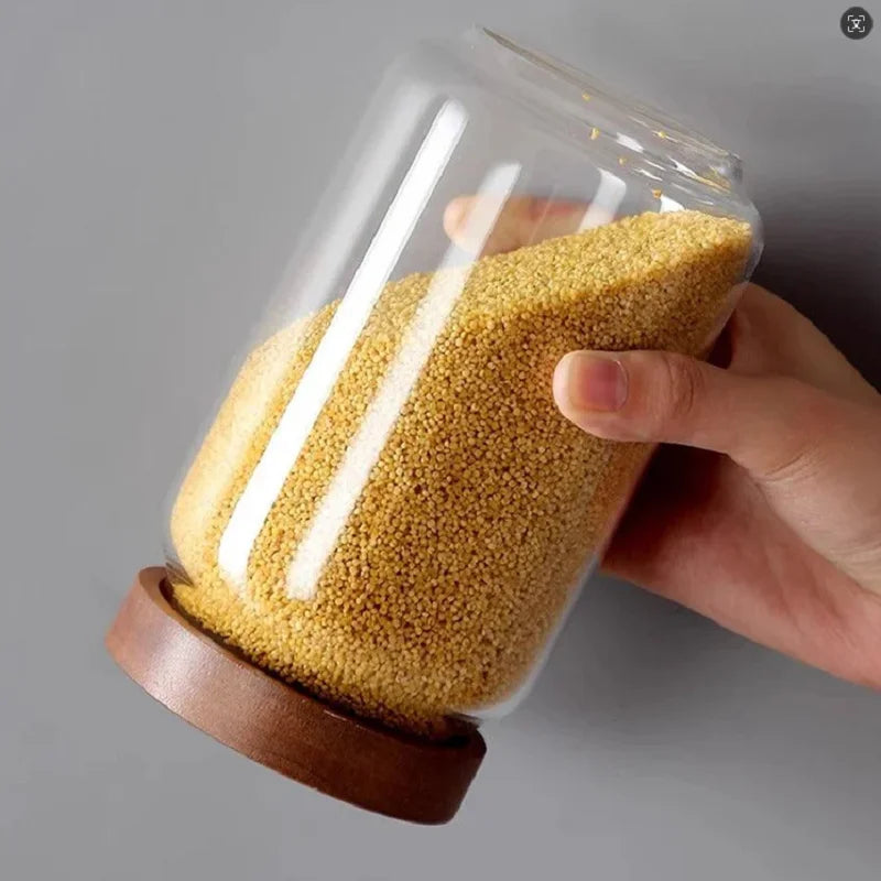 Hand holding a glass jar filled with yellow grains on a gray background