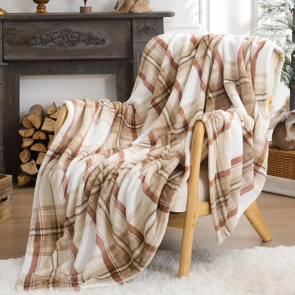 A beige plaid blanket draped over a wooden chair in a cosy room with a fireplace and logs.