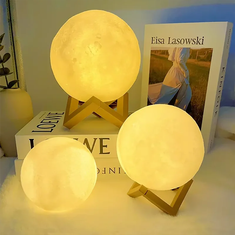 Three moon-shaped lamps on a surface with books in the background