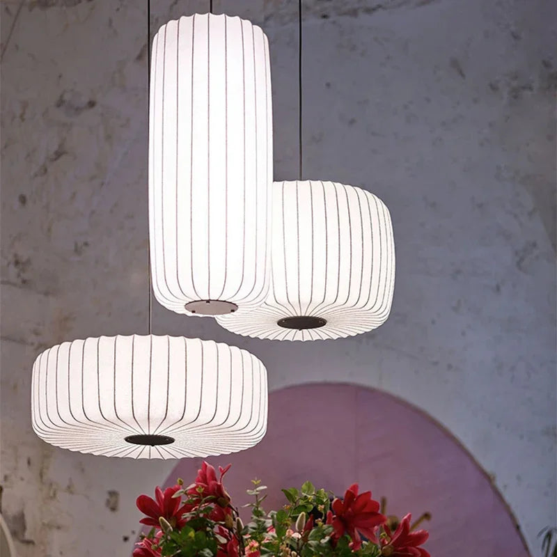 Three white pendant lights hanging against a textured wall with flowers in the foreground.