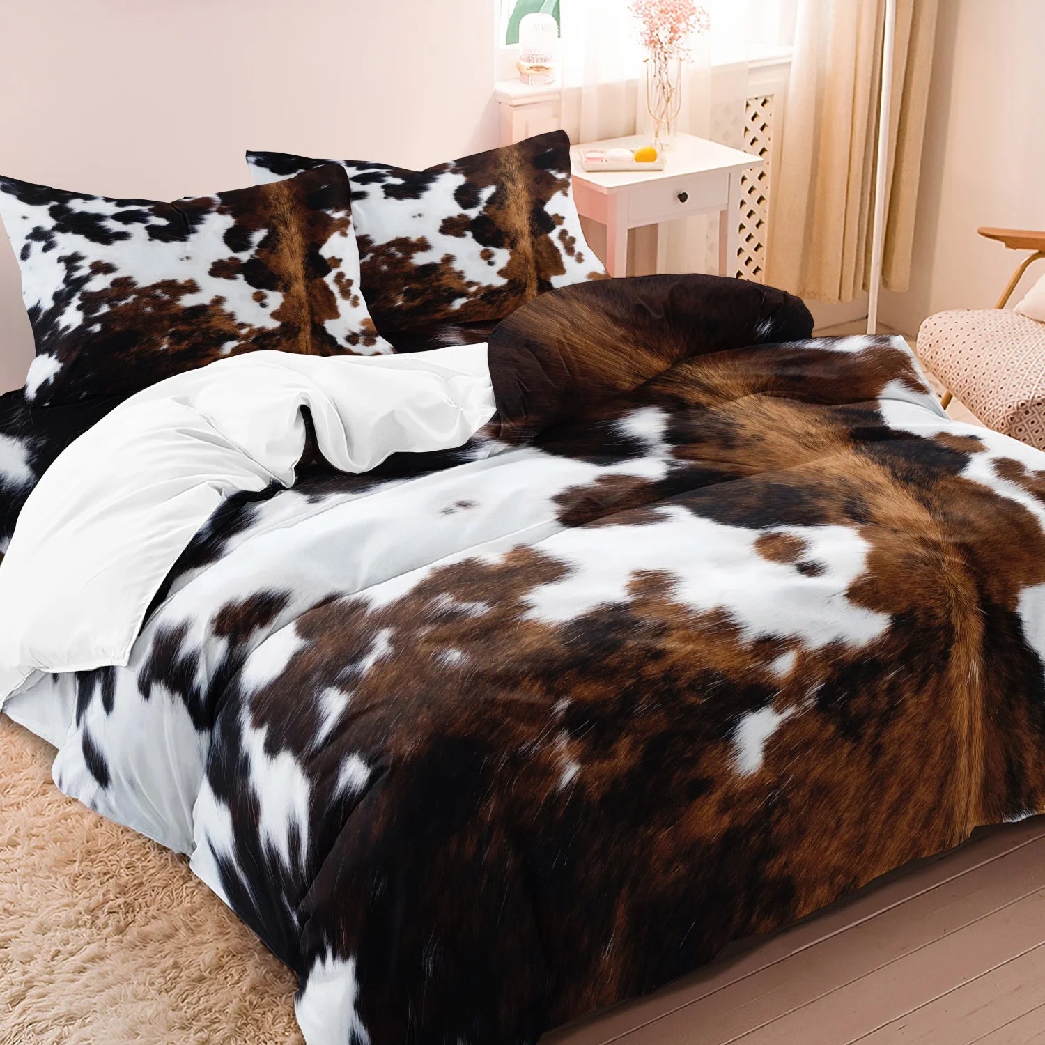 Brown, black, and white cow-print 3-piece bedding set with matching pillowcases in a neutral bedroom.