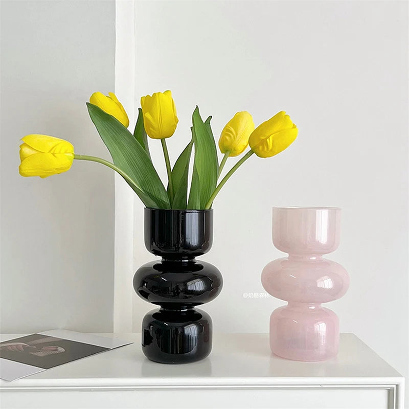 Black and pink vases with yellow tulips on a white surface