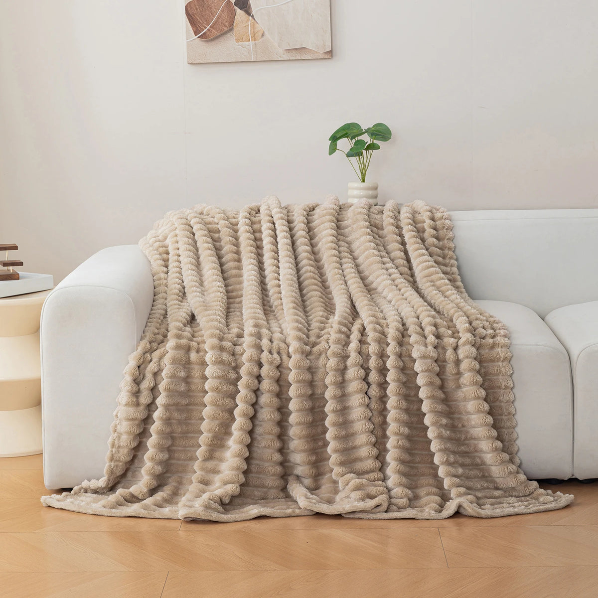 Beige textured blanket draped over a white sofa in a living room setting.