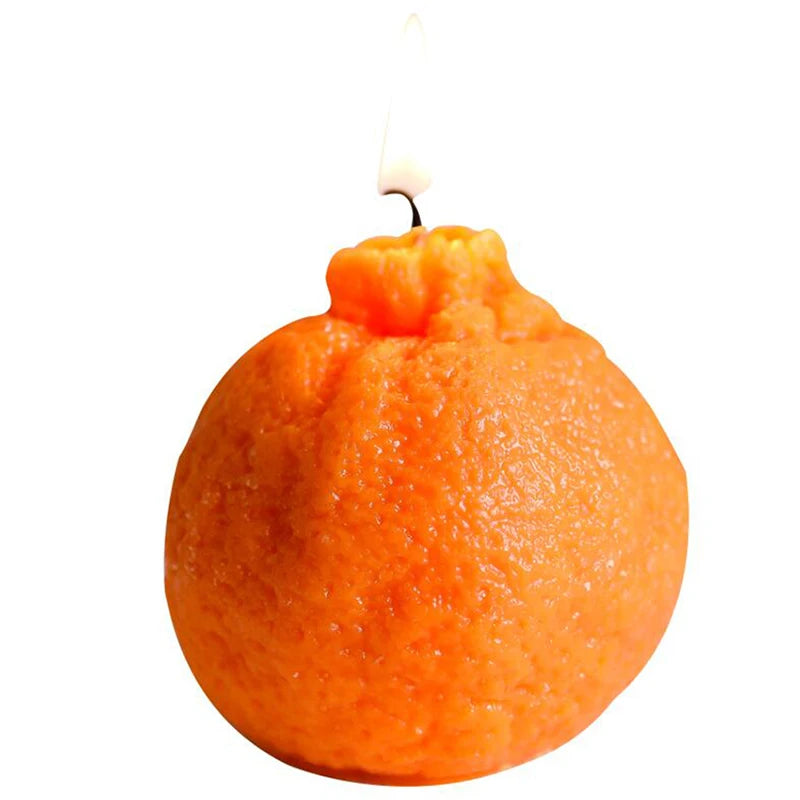 Orange candle with a lit wick on a white background