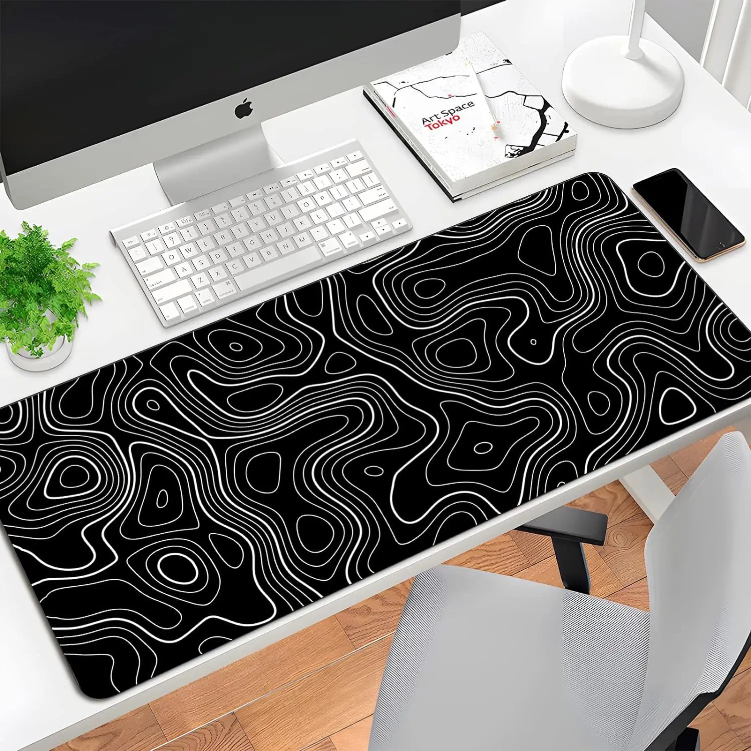 Black and white topographic desk mat on a desk with office items.