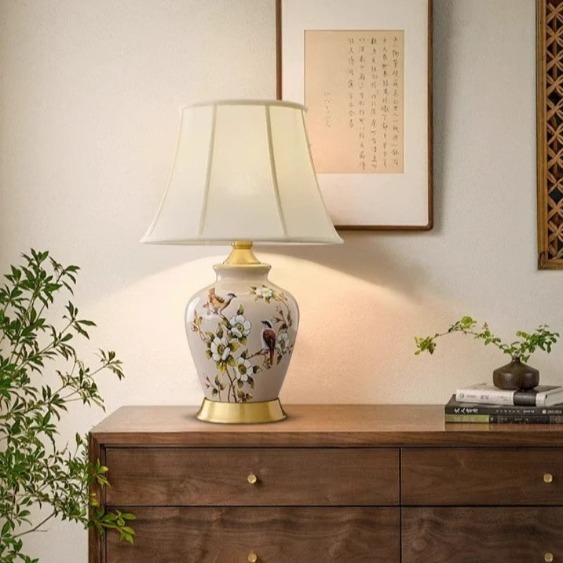 Decorative table lamp with floral design on a wooden cabinet.