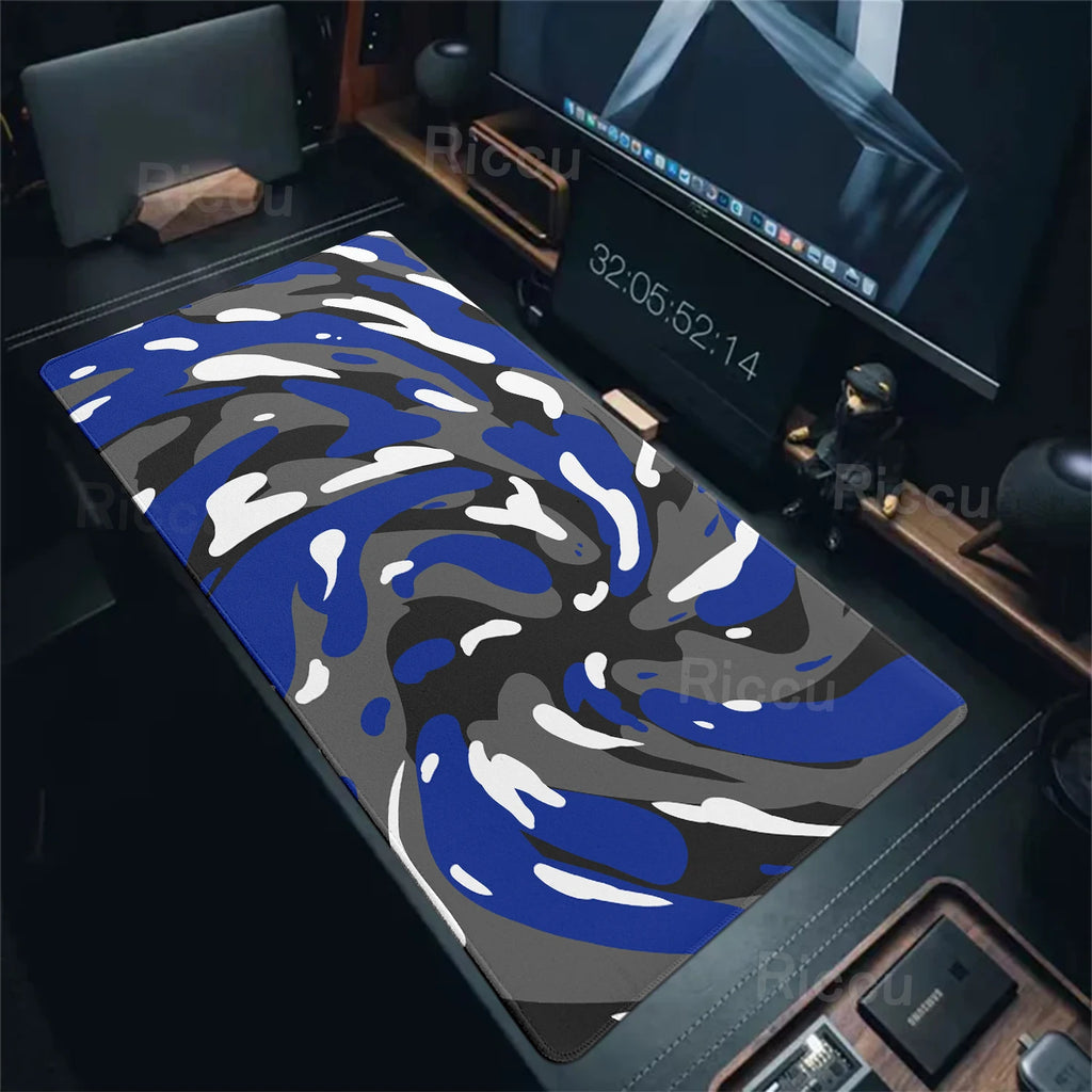 Blue and grey camouflage desk mat on a desk with computer equipment.