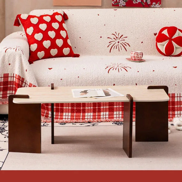 A cream-coloured quilted sofa cover featuring red fireworks and heart patterns with a checkered fringe.