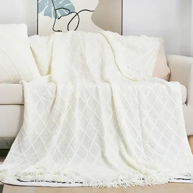 White textured knit throw with a diamond weave and fringed hem styled over a cream sofa