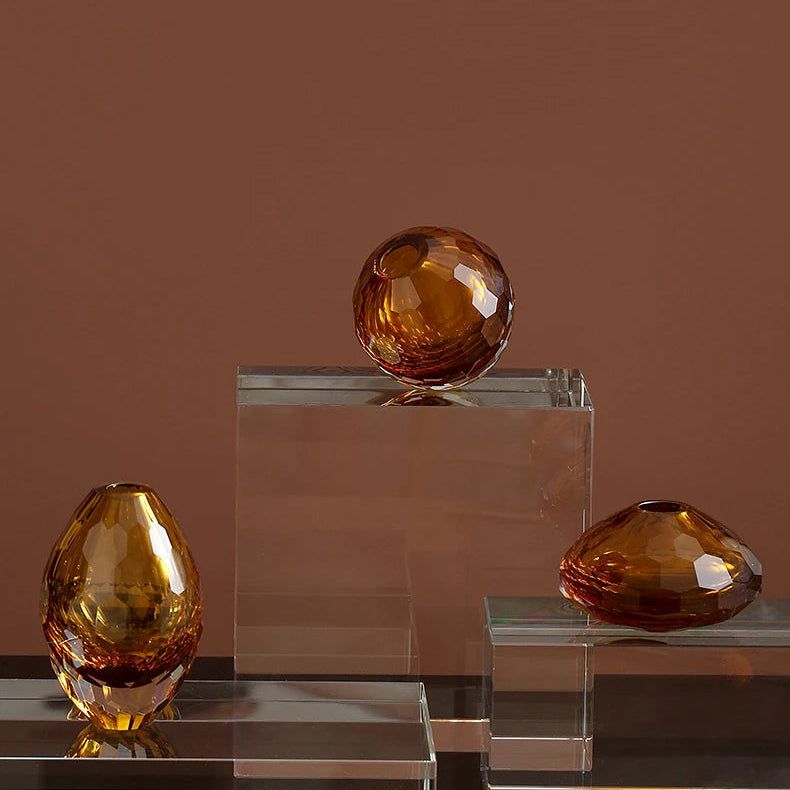 Three amber-coloured crystal balls on clear stands against a brown background