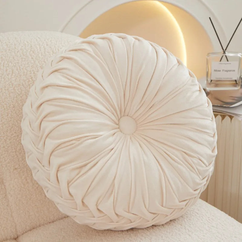 Round beige cushion on a couch.
