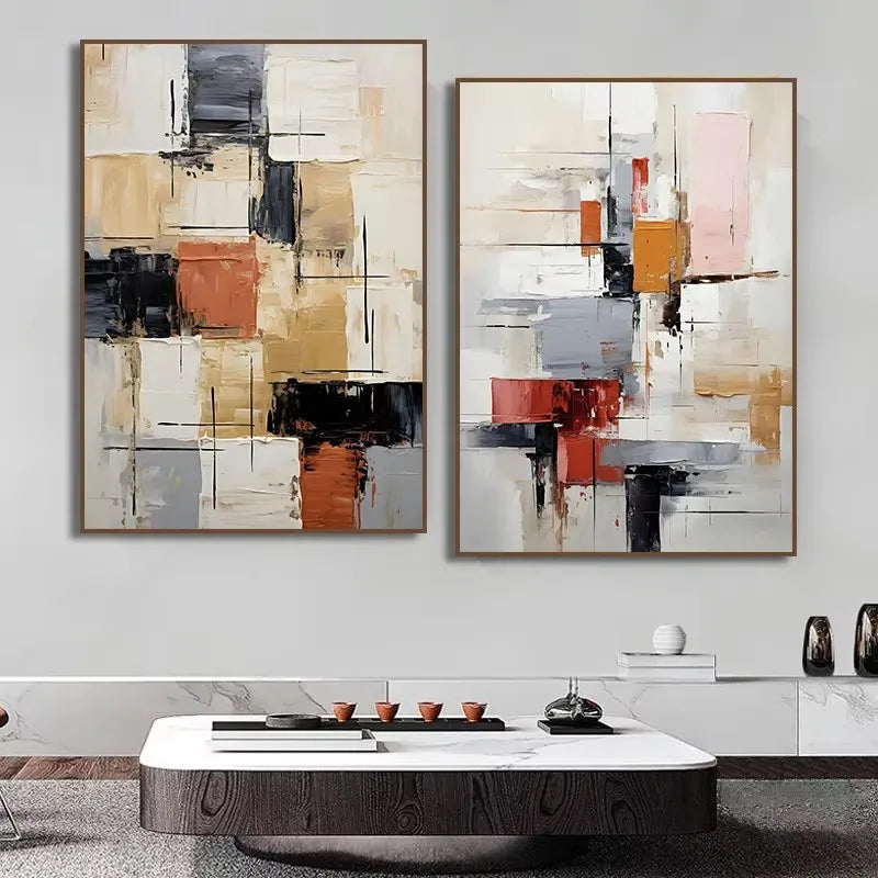 Two abstract art pieces hanging on a wall above a coffee table.