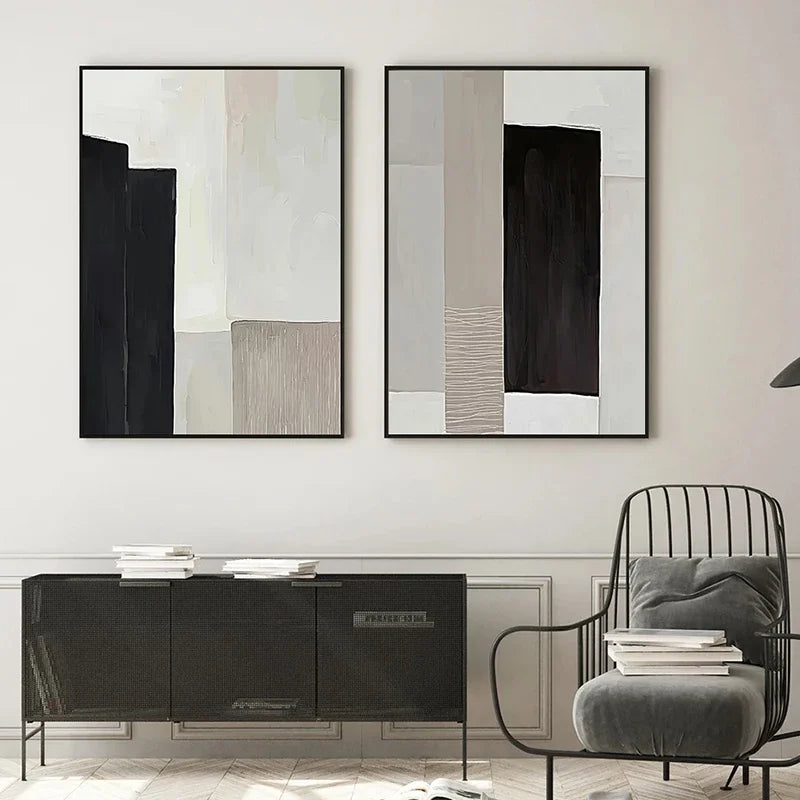 Two abstract art pieces on a wall above a modern black console table with a gray chair.