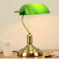 Green glass banker-style desktop lamp with antique brass metal base and pull-chain detail