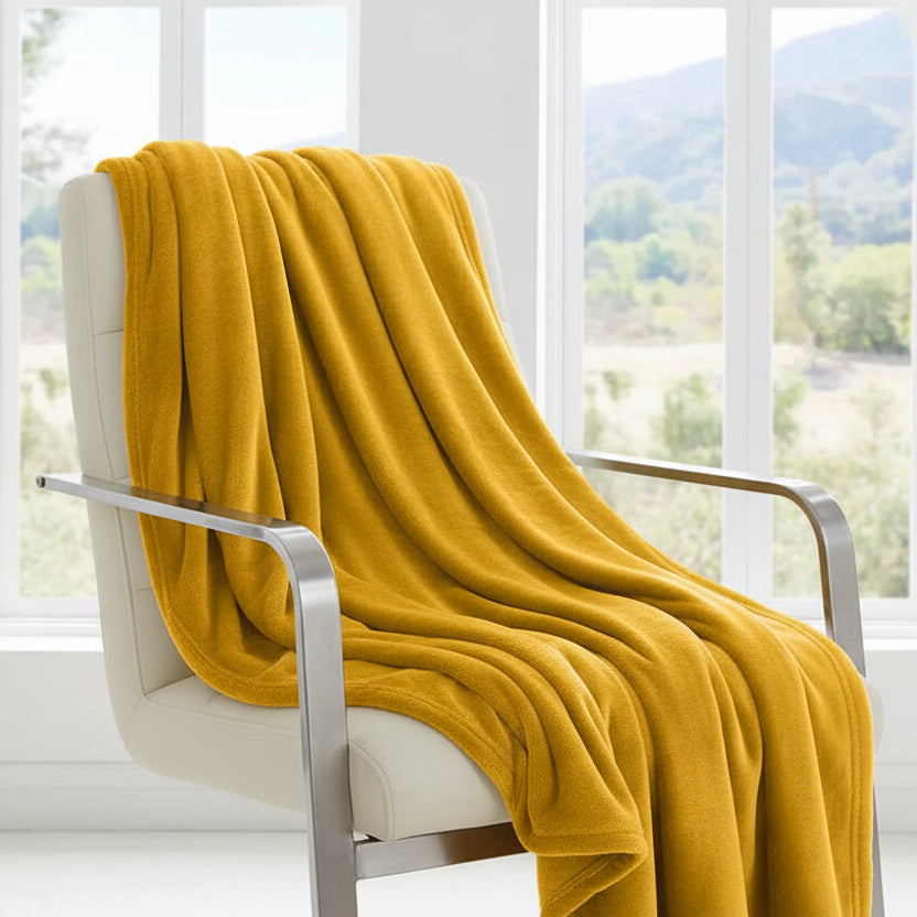 Yellow blanket on a bed with a window view of trees and mountains