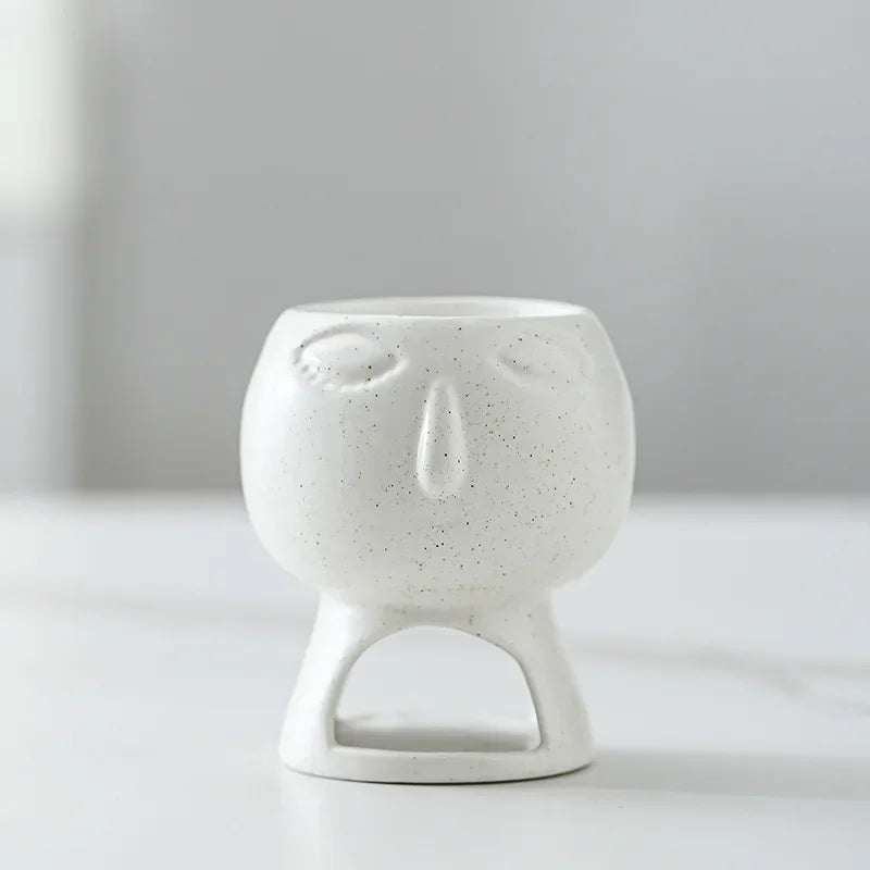 White ceramic incense burner with face design on a light gray background