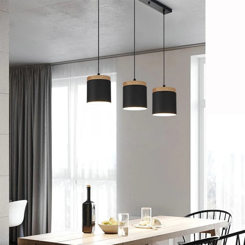 Modern dining room with a wooden table, black chairs, and pendant lights.