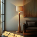 Sculptural wood floor lamp with curved hourglass base and warm fabric shade, 160cm