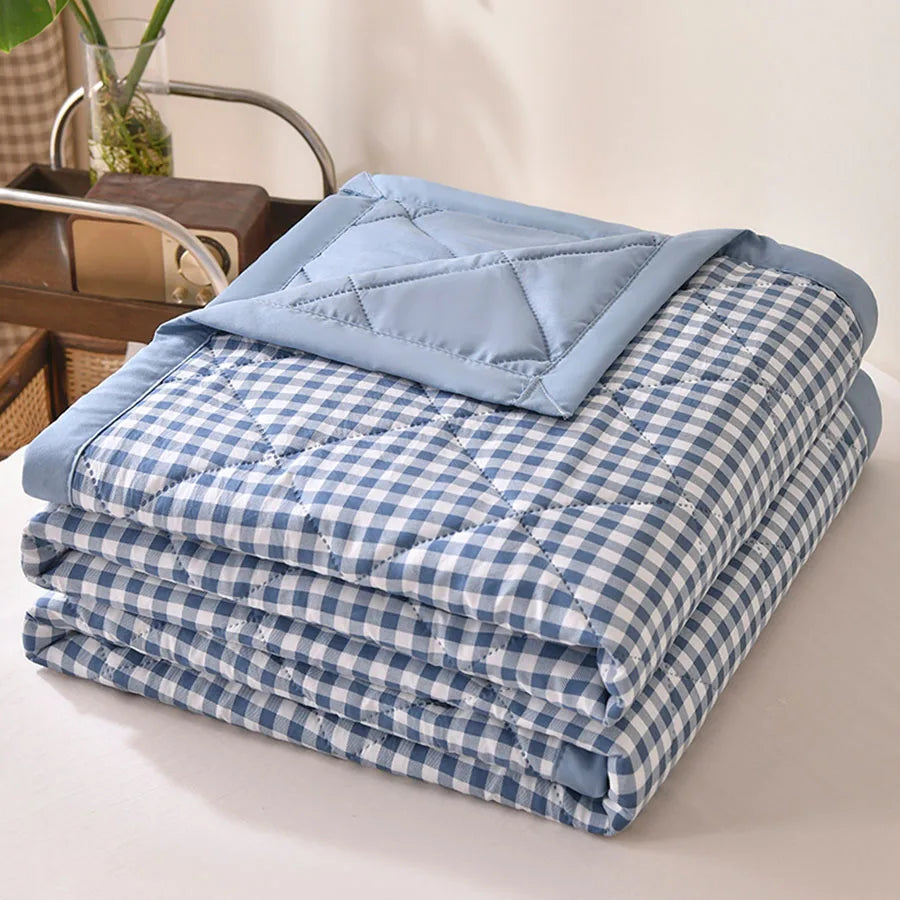 Blue and white gingham quilted comforter folded on a bed with a light blue border