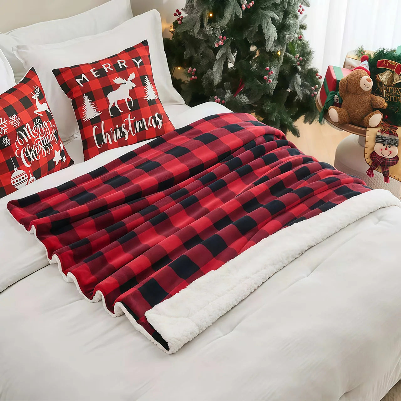 Red and black plaid blanket on a bed with Christmas-themed pillows and decorations.
