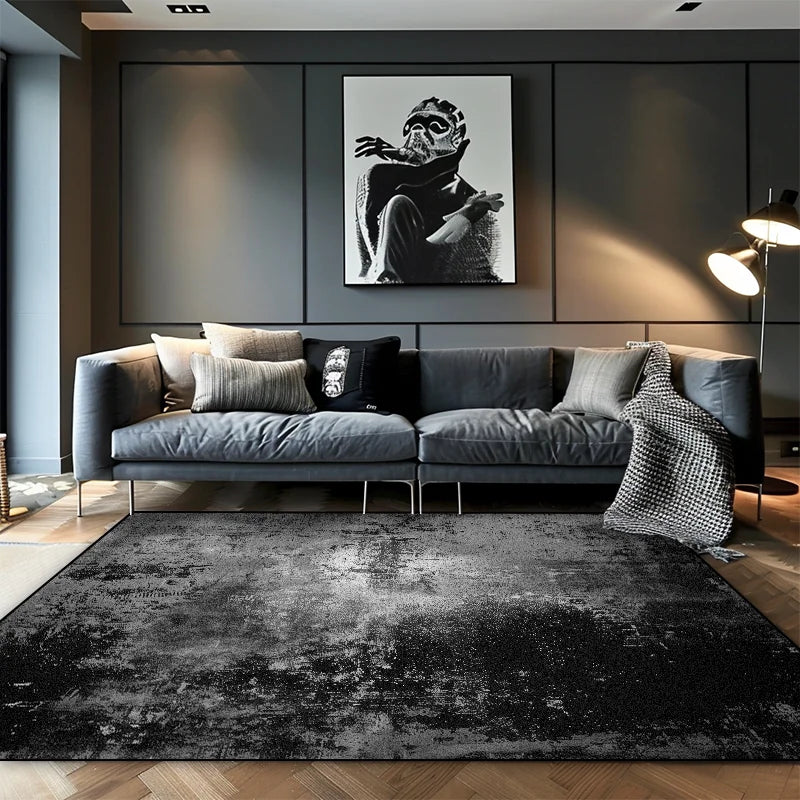 Dark black and grey ombre abstract area rug with distressed texture in a contemporary dark living room with grey sofa