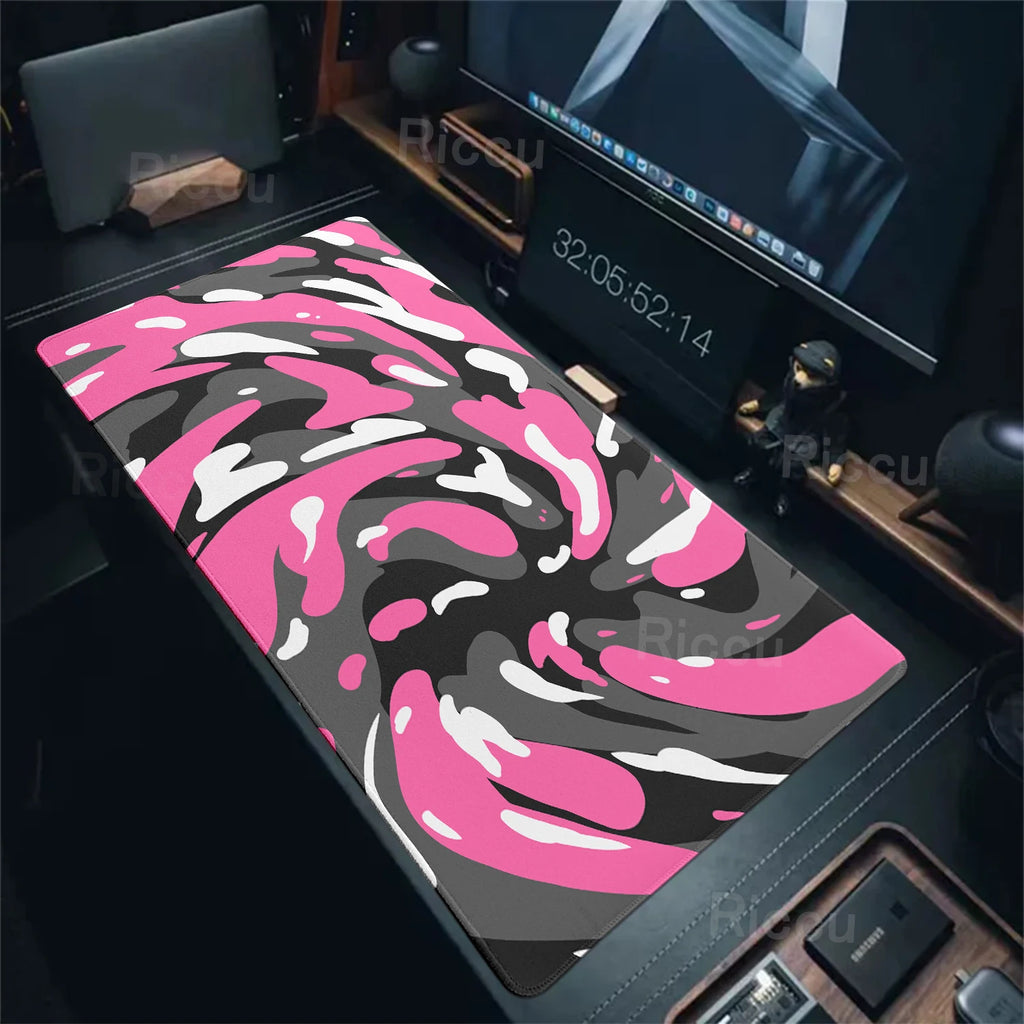 Pink and black camouflage mouse pad on a desk with computer equipment.