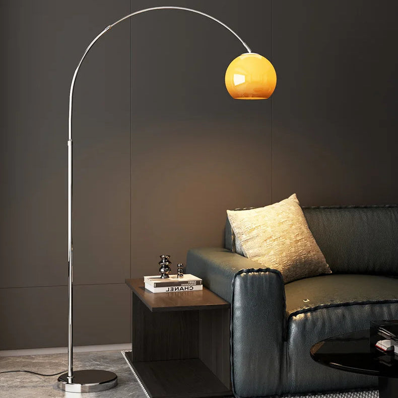 Mushroom-shaped Bauhaus floor lamp with arched metal frame and amber glass shade beside a black leather sofa