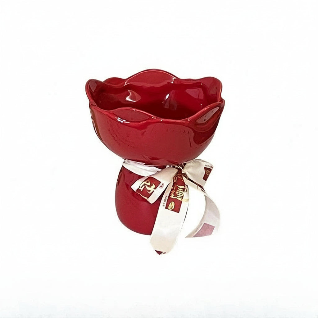 Red ceramic rose-shaped bowl with a white ribbon on a white background