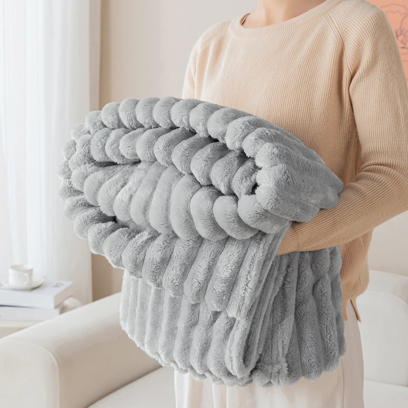 Person holding a large gray textured blanket in a home setting