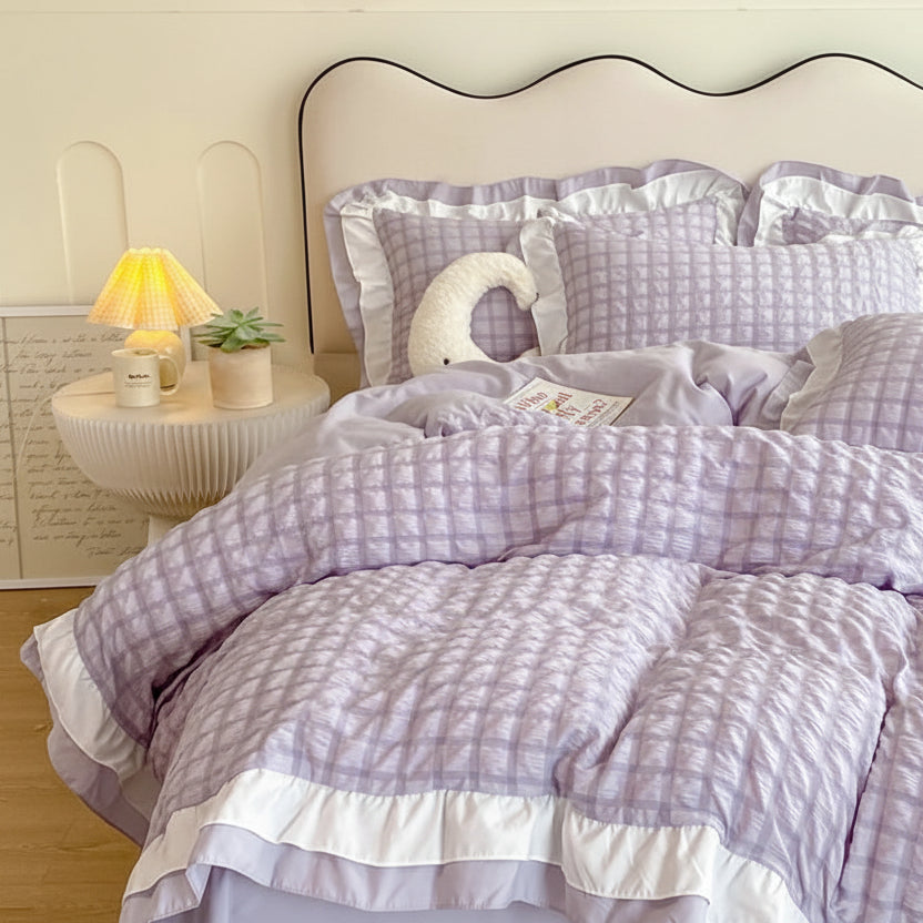 Purple checkered duvet set on a bed with a nightstand and lamp in the background.