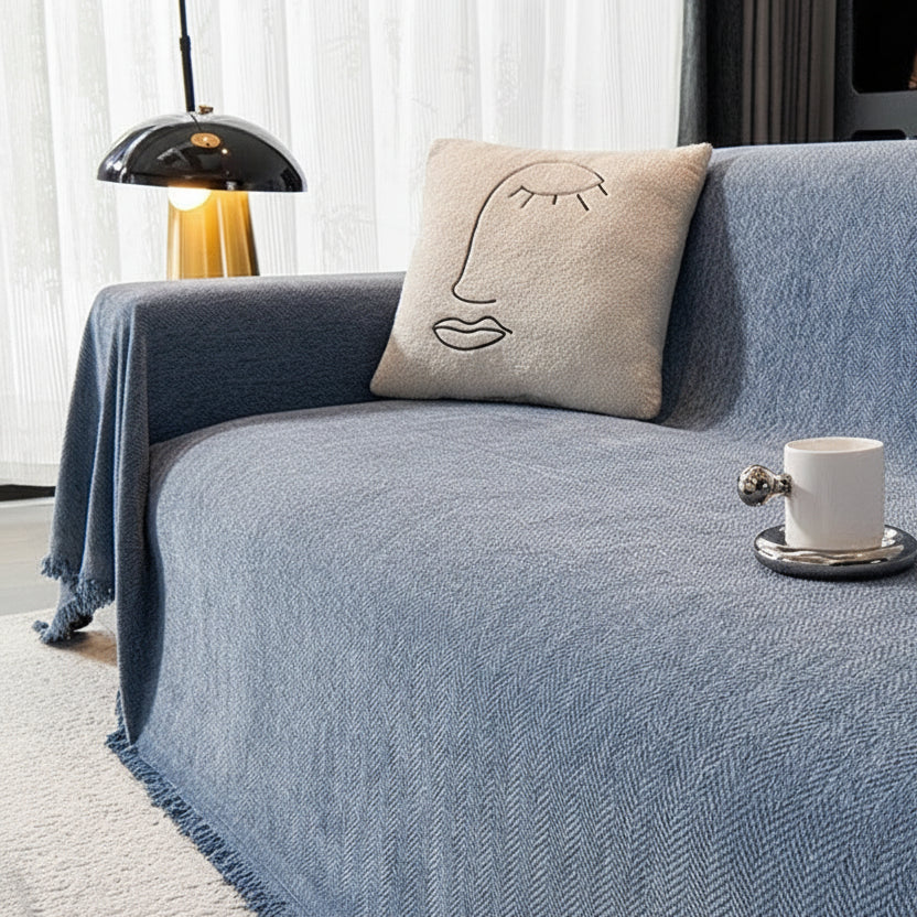 Denim Blue herringbone throw blanket styled on a sofa with a face-motif cushion.