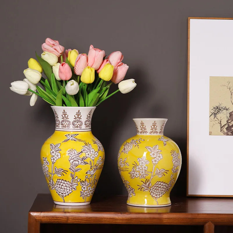 Two yellow vases with floral patterns on a wooden surface against a dark wall.