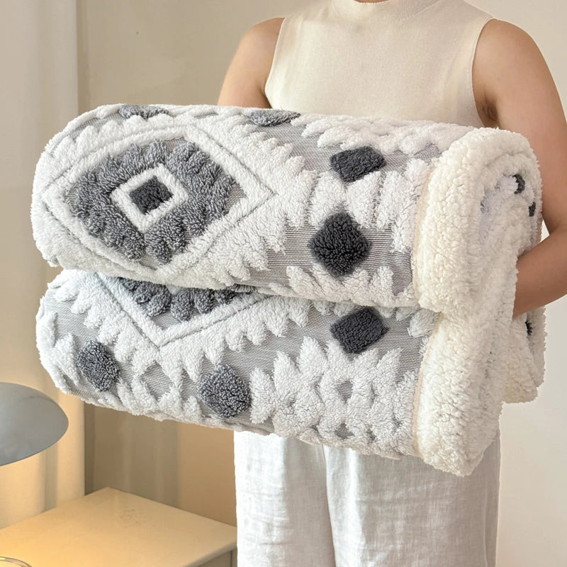 Person holding a textured charcoal grey and white blanket with geometric patterns.