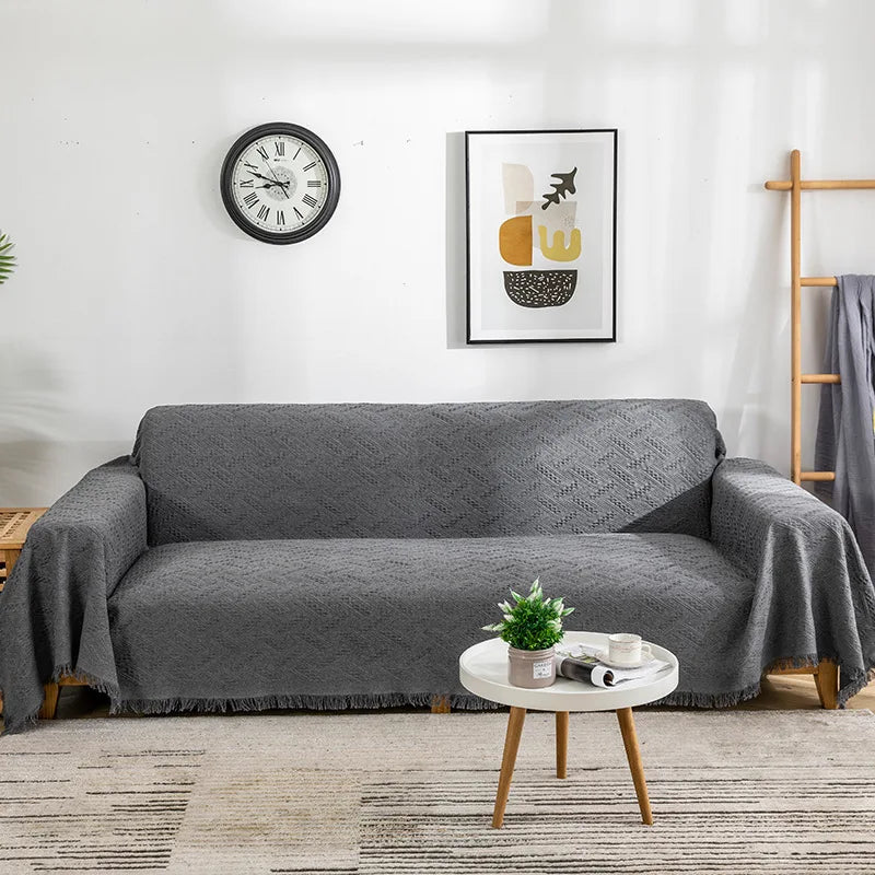 Charcoal grey sofa cover draped over a modern couch with a textured woven pattern