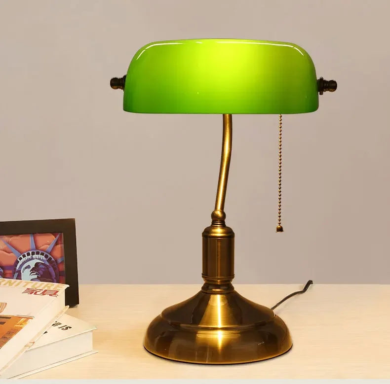 Green glass banker-style desktop lamp with antique brass metal base and pull-chain detail