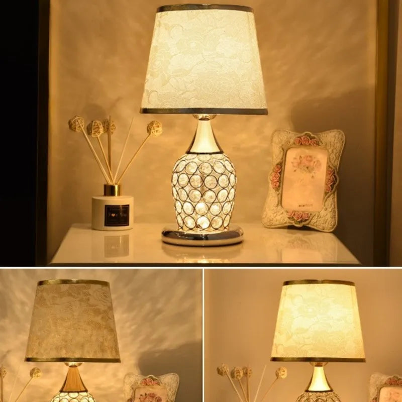Gold crystal-lattice bedside lamp with gold scrollwork fabric shade on a nightstand.