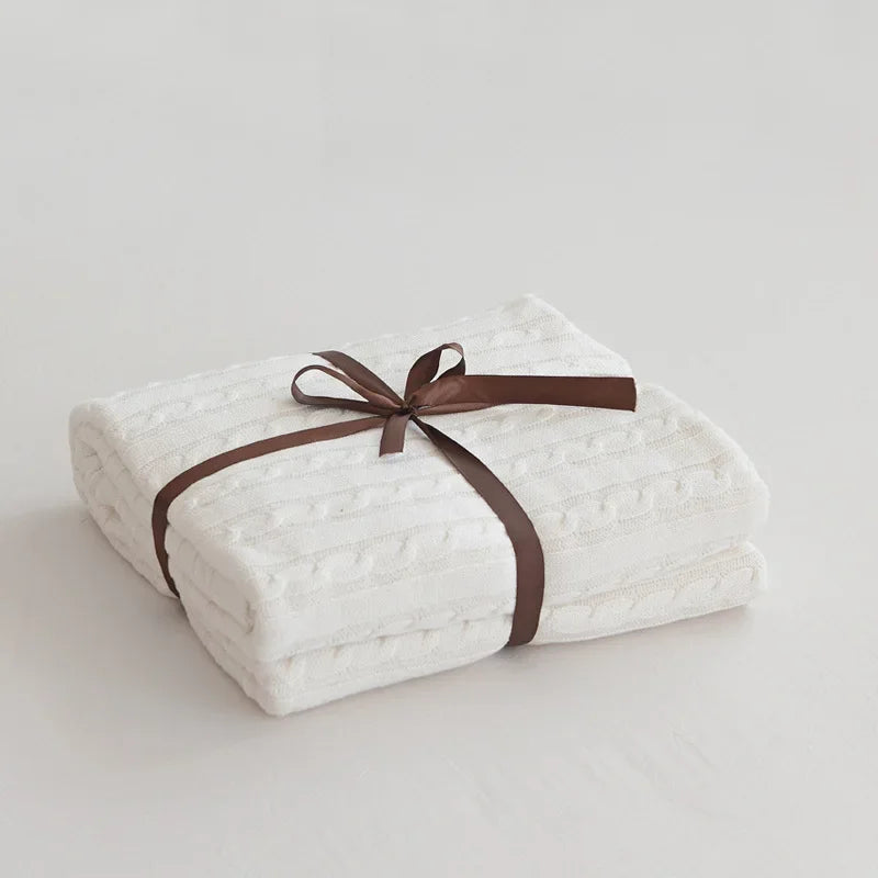 White quilt with a brown ribbon on a light gray background