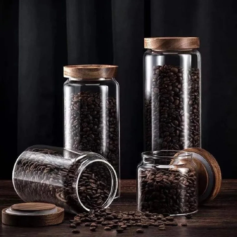 Glass jars with wooden lids filled with coffee beans on a dark background