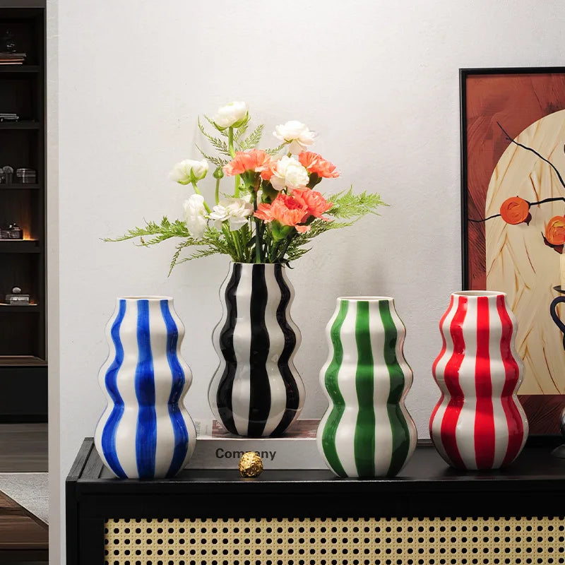 Four colourful striped vases on a shelf with a vase of flowers.