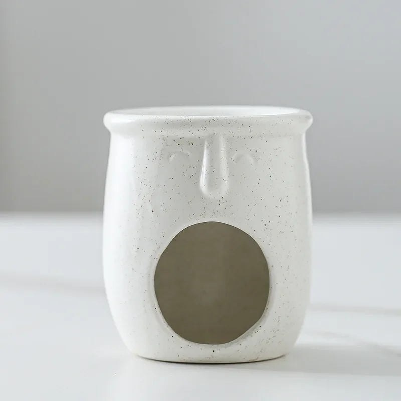 Speckled white ceramic oil burner with a central circular design on a light gray background
