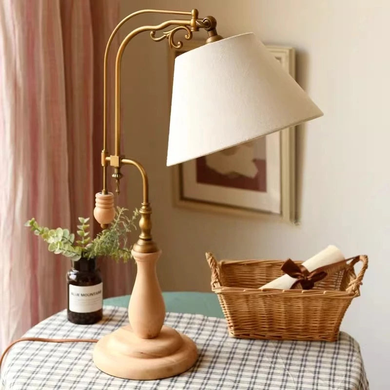 Wood and brass table lamp with ivory fabric shade on a styled table