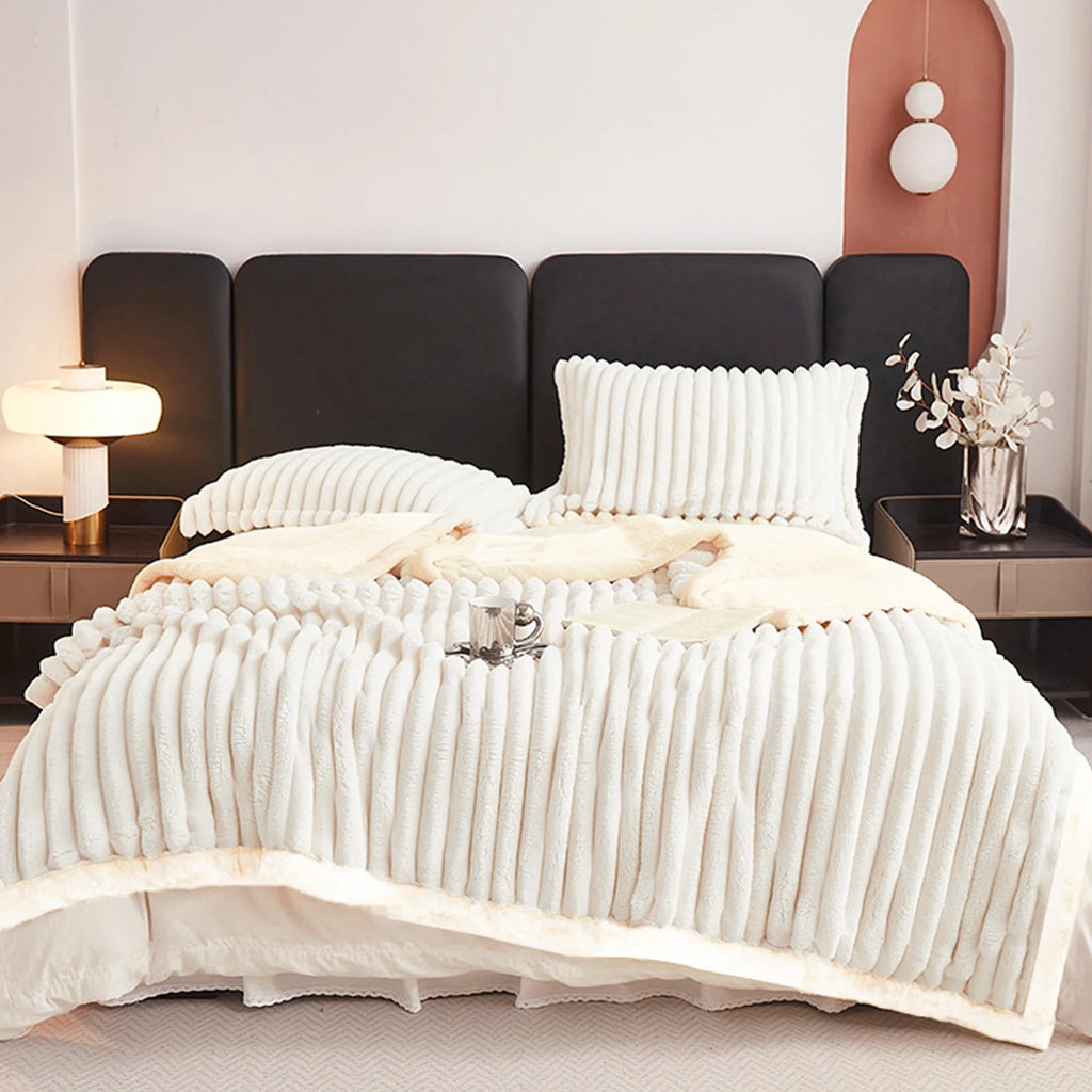 Bedroom with a bed featuring ivory white bedding and pillows, nightstands with lamps, and a vase with flowers.